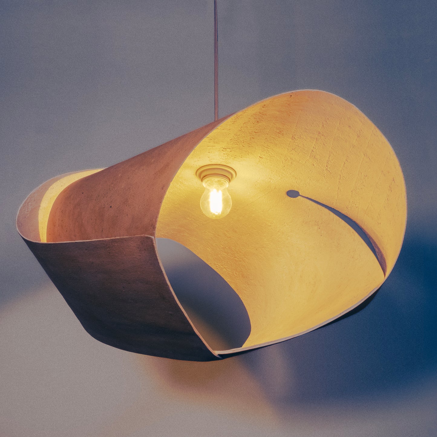Luminaire évoquant les toit des bâtiments de l'architecture traditionnelle japonaise. Un luminaire artisanal en papier recyclé fabriqué à partir d'une seul feuille de épaisse et courbée.