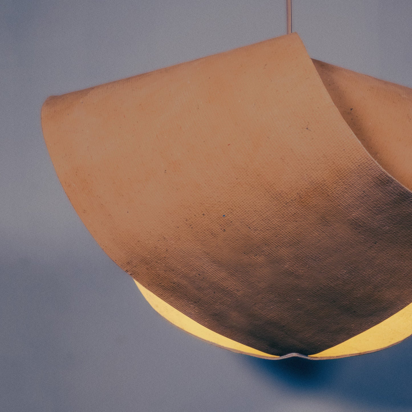 Luminaire évoquant les toit des bâtiments de l'architecture traditionnelle japonaise. Un luminaire artisanal en papier recyclé fabriqué à partir d'une seul feuille de épaisse et courbée.